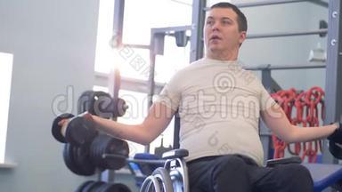 一名有两个哑铃的残疾男子在健身房的训练课程